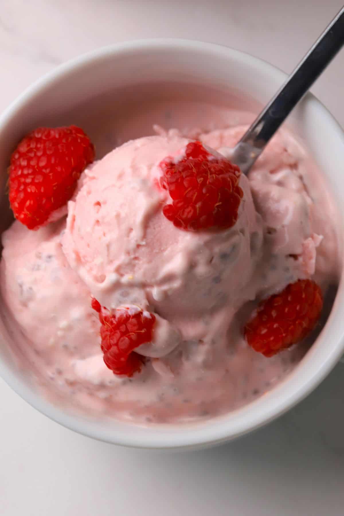Low carb raspberry chia cottage cheese ice cream in a bowl topped with fresh raspberries.
