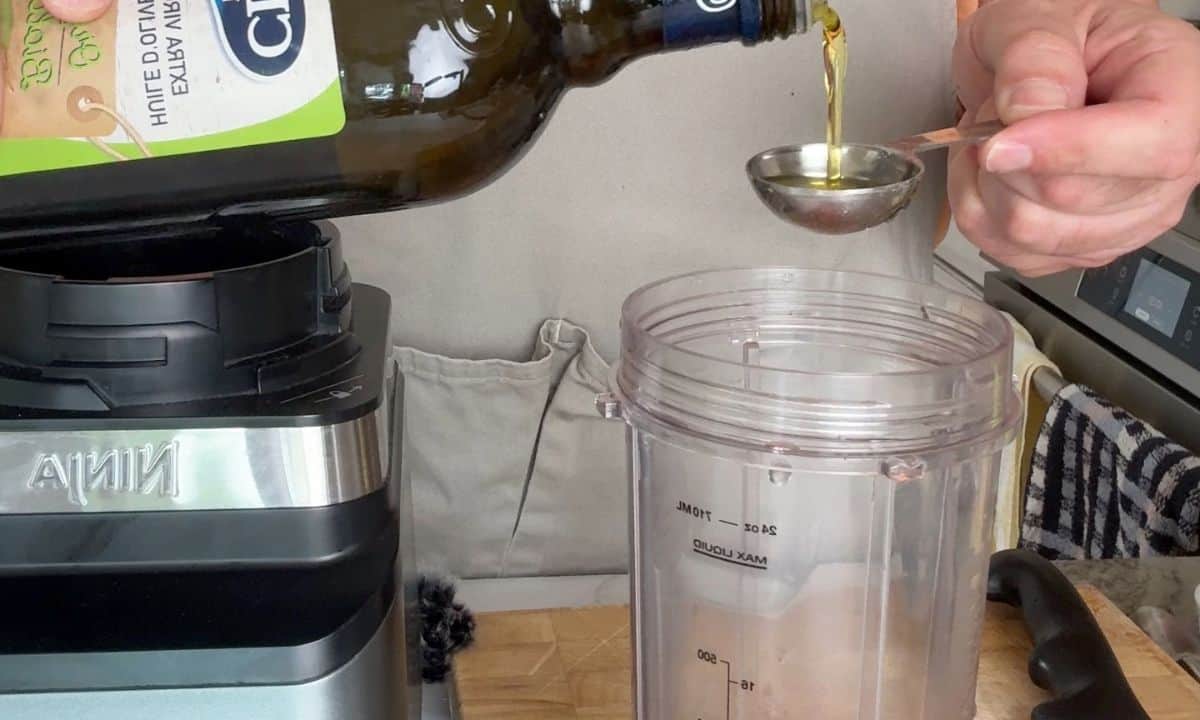 Adding olive oil to the blender.