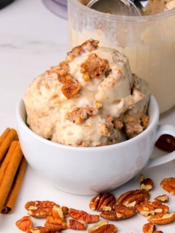 Low carb cinnamon pecan crunch ice cream scoops in a bowl and a ninja creami pint next to the bowl.