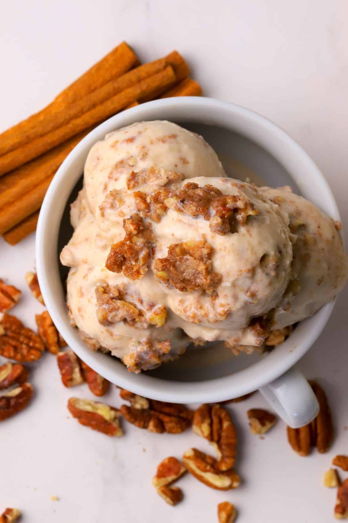 Low carb cinnamon pecan crunch ice cream scoops in a bowl and a ninja creami pint next to the bowl.