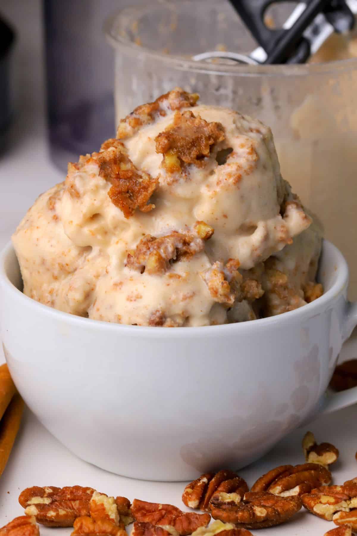 Low carb cinnamon pecan crunch ice cream scoops in a bowl and a ninja creami pint next to the bowl.