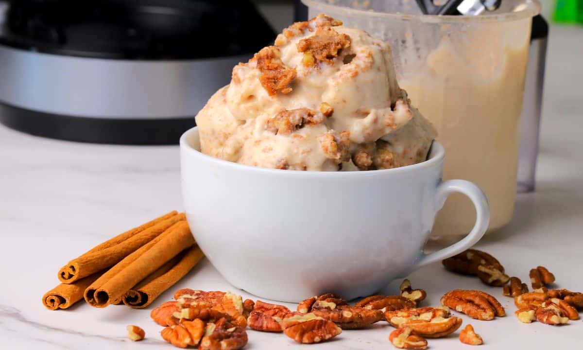Low carb cinnamon pecan crunch ice cream scoops in a bowl and a ninja creami pint next to the bowl.