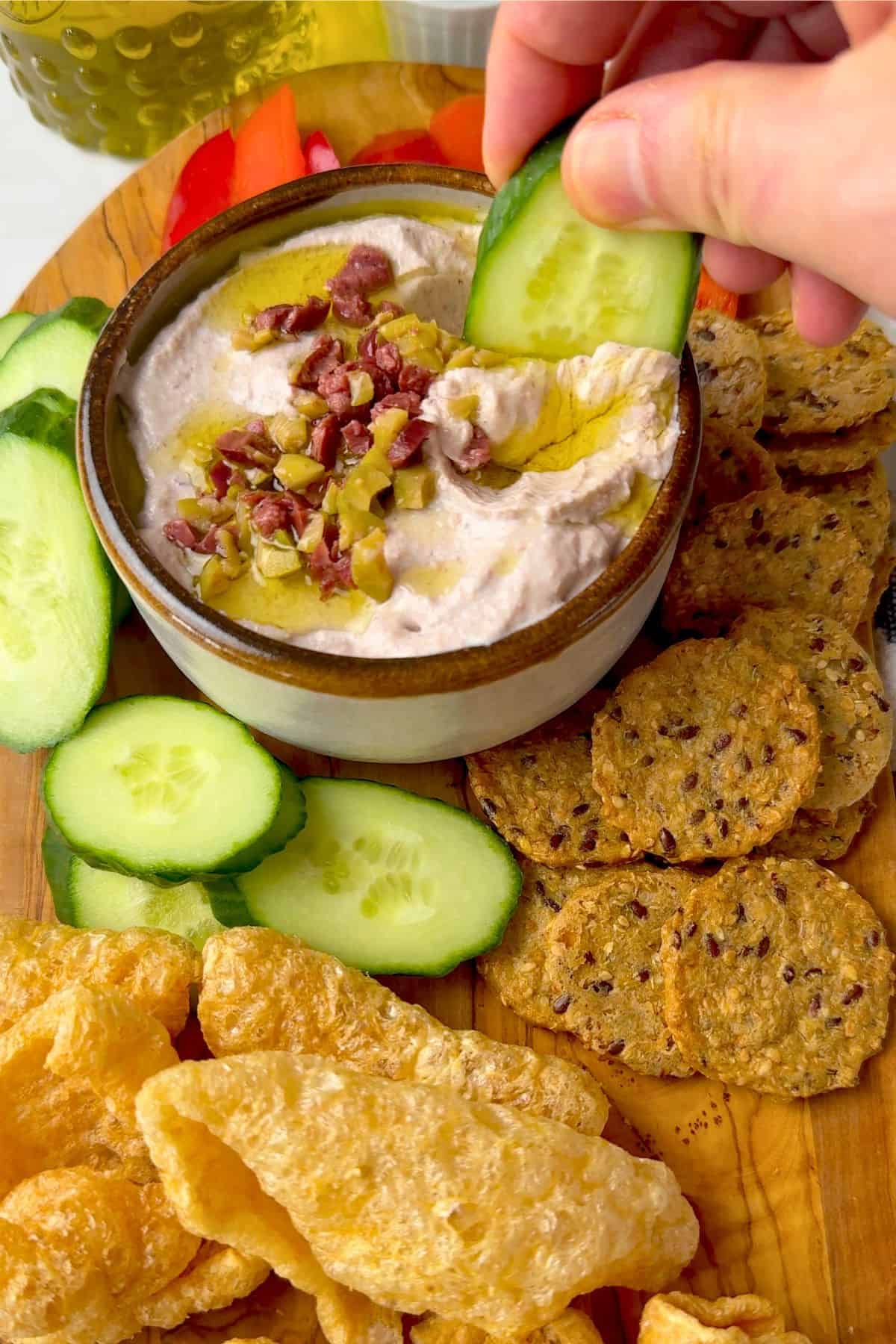 Dipping a cucumber slice into the low carb olive cottage cheese dip.
