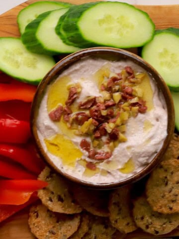 Low carb olive cottage cheese dip in a bowl surrounded by an assortment of dipping options.