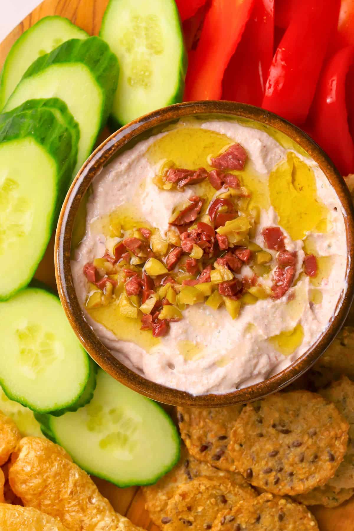 Low carb olive cottage cheese dip in a bowl surrounded by an assortment of dipping options.