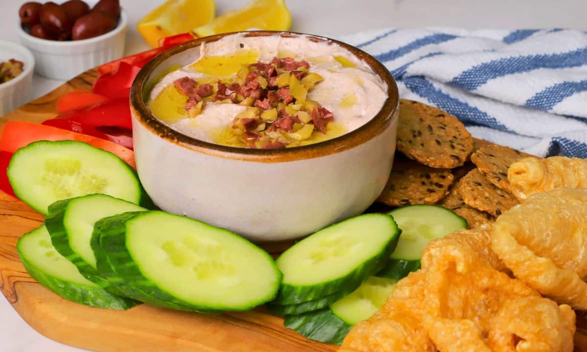 Low carb olive cottage cheese dip in a bowl surrounded by an assortment of dipping options.