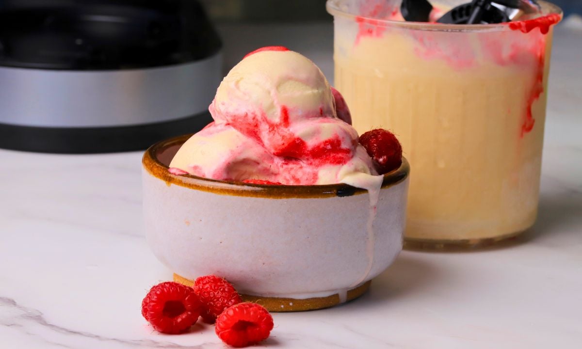 Scoops of low carb peanut butter raspberry ice cream made in the ninja creami in a bowl next to the pint.