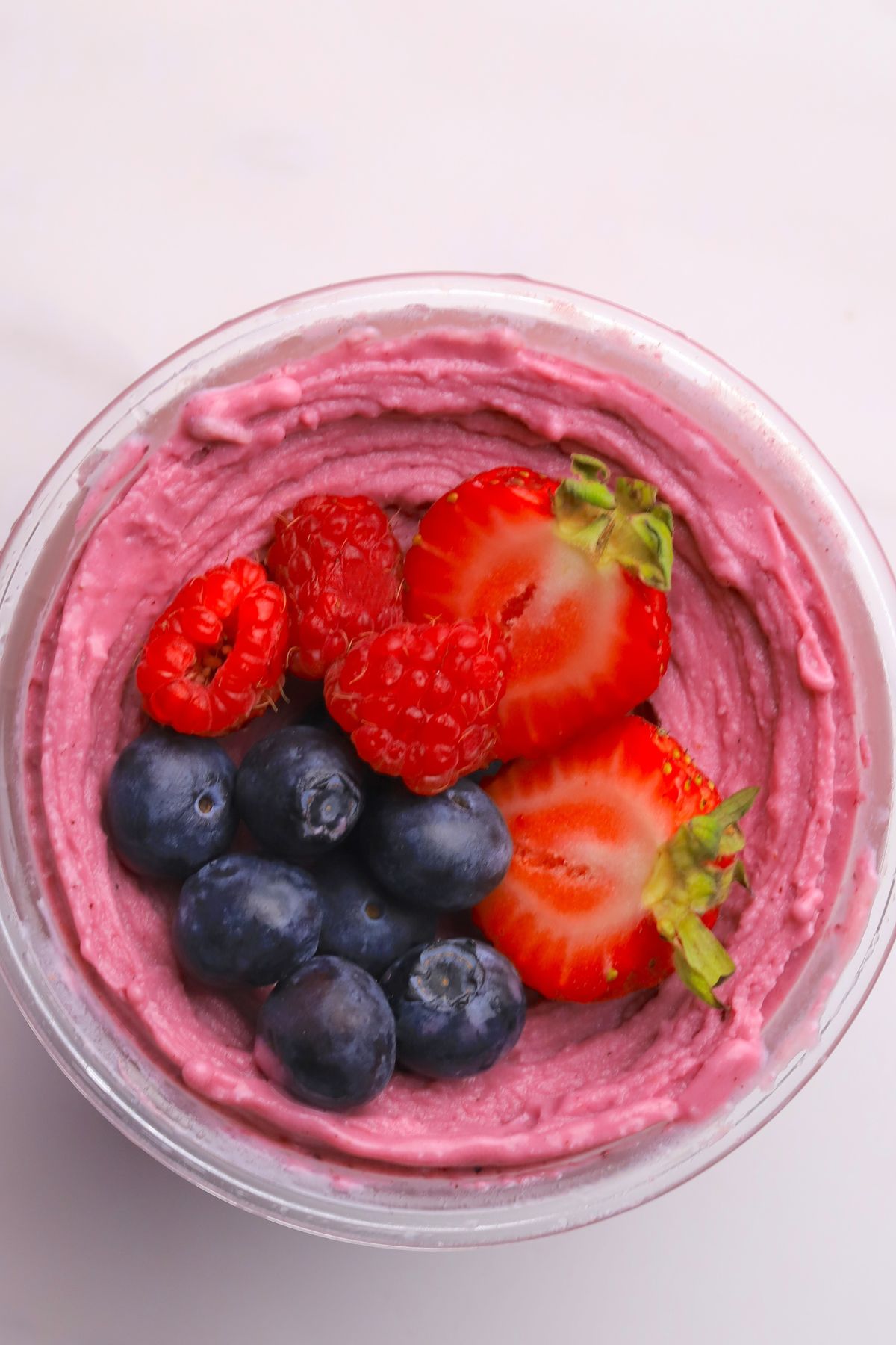 Ninja creami low carb triple berry ice cream in a ninja creami pint with fresh berries.
