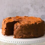 Diabetic chocolate birthday cake on a cake plate with one slice missing.