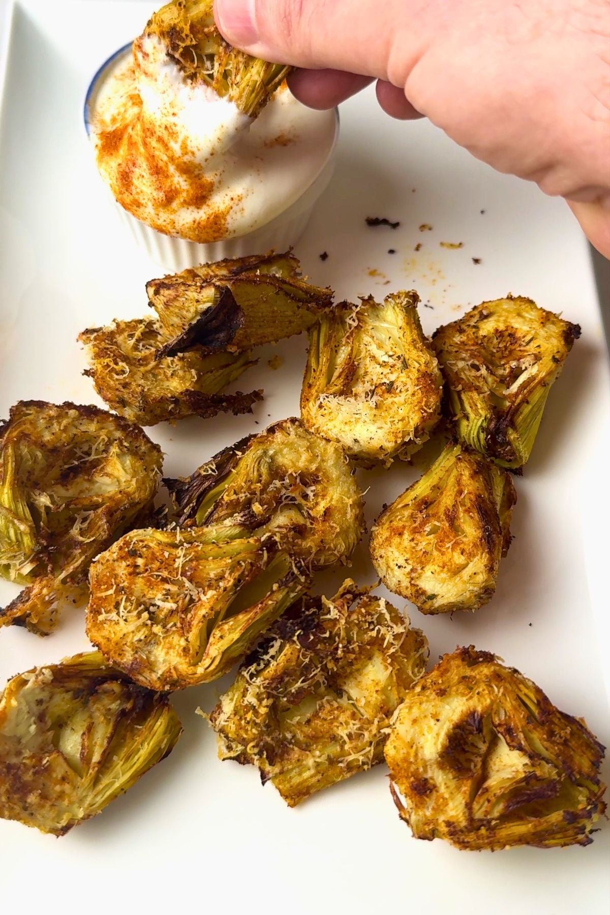 Dipping an air fried artichoke in a dip.