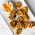 Low carb air fryer artichokes on a platter with a dip.