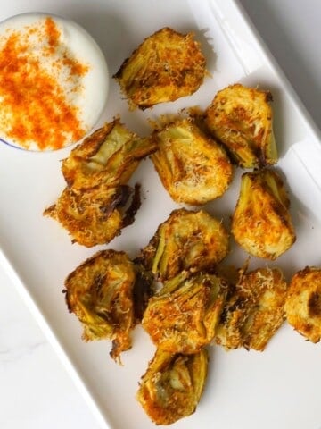 Low carb air fryer artichokes on a platter with a dip.