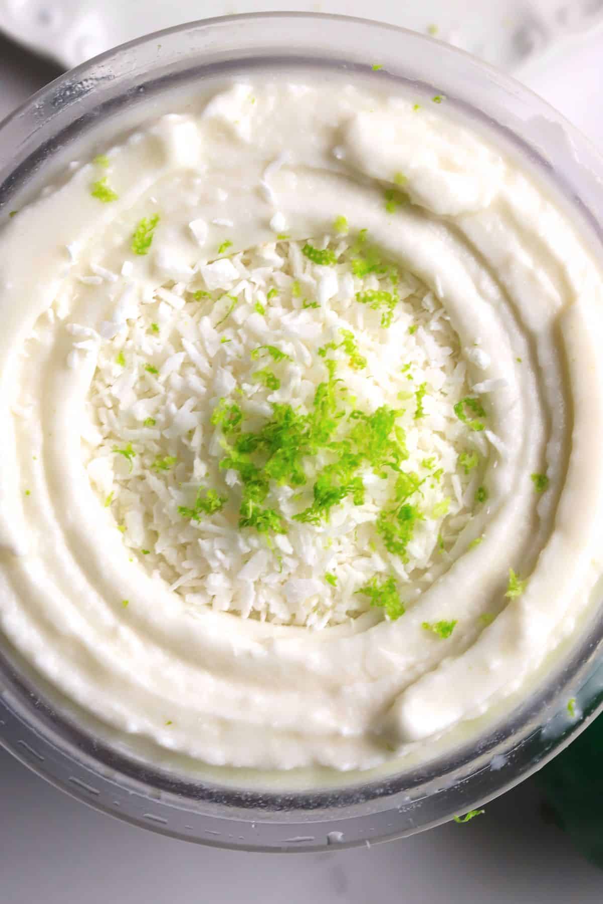 Ninja creami pint with ice cream and lime and coconut flakes on top.