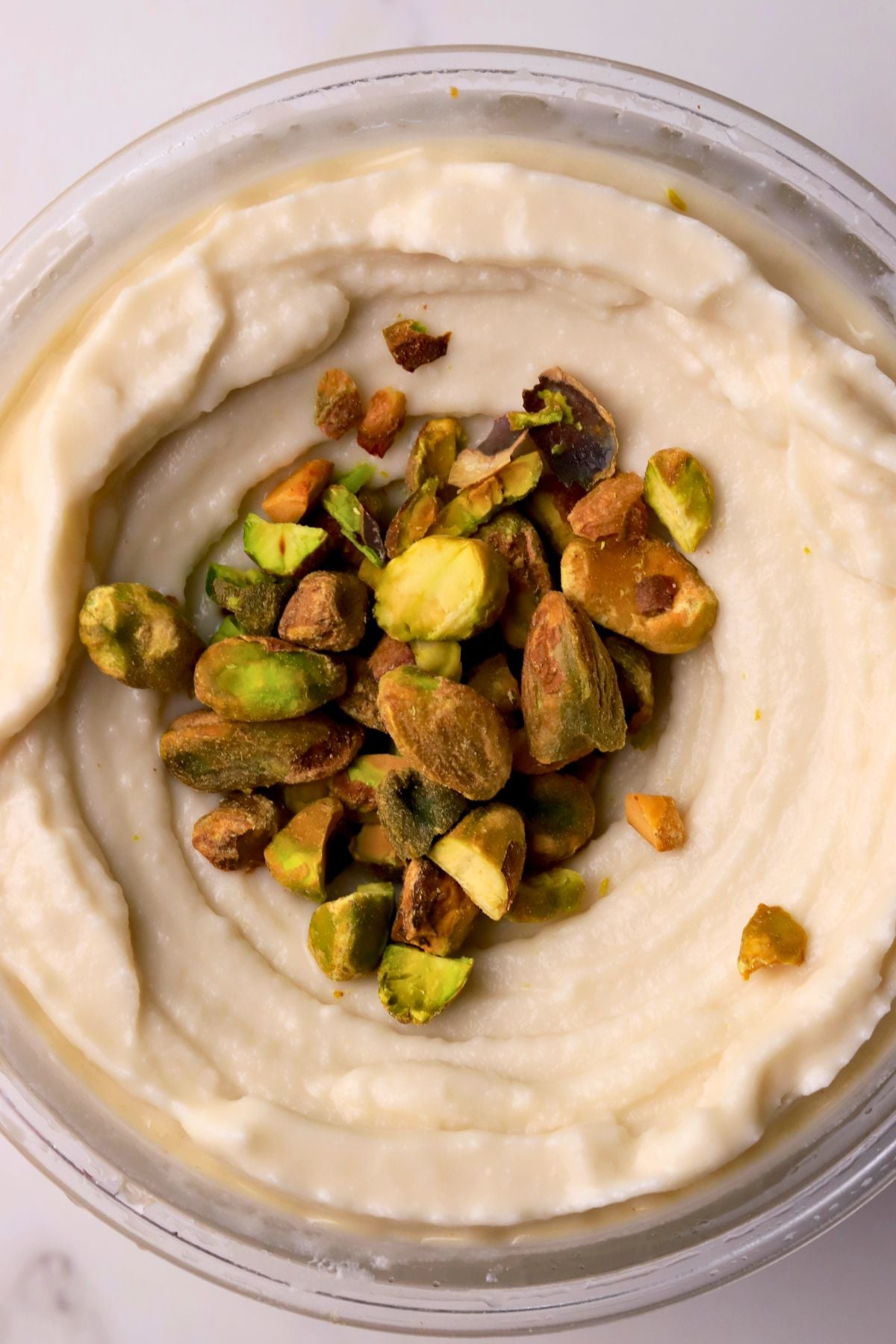 Low carb pistachio almond ice cream in the ninja creami pint topped with crushed pistachios.