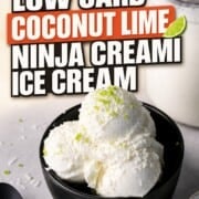 Scoops of low carb coconut lime ice cream in a black bowl with the ninja creami pint in the background.