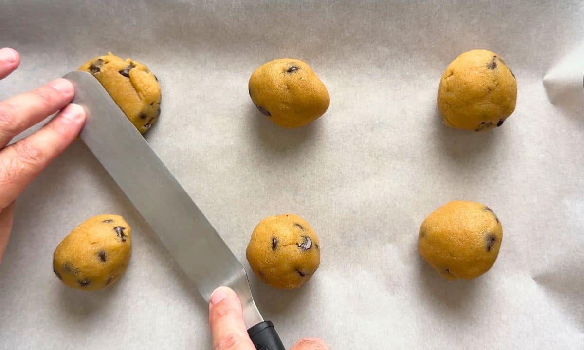 Flatting the cookie dough balls on the baking tray.