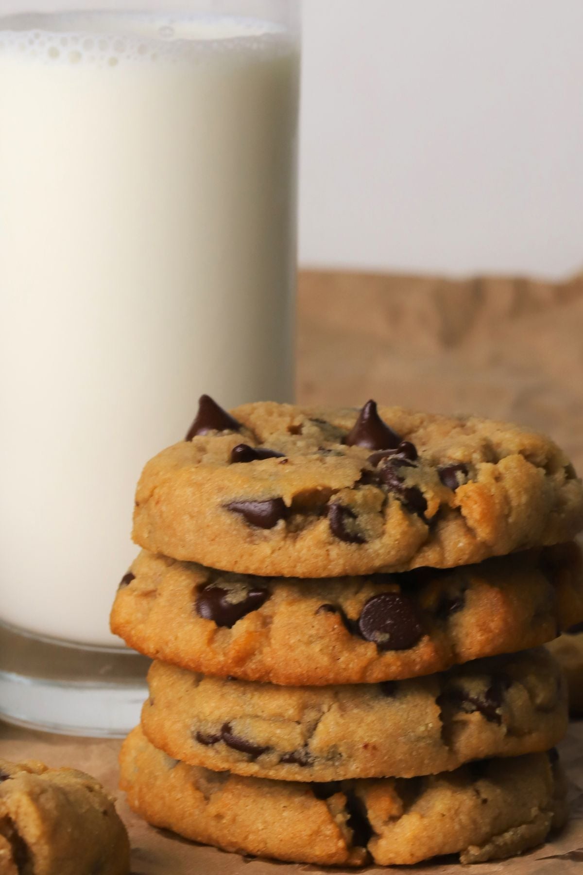 Low carb chocolate chip cookies stacked on top of each other next to a glass of milk.