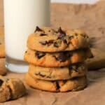 Low carb chocolate chip cookies stacked on top of each other next to a glass of milk.