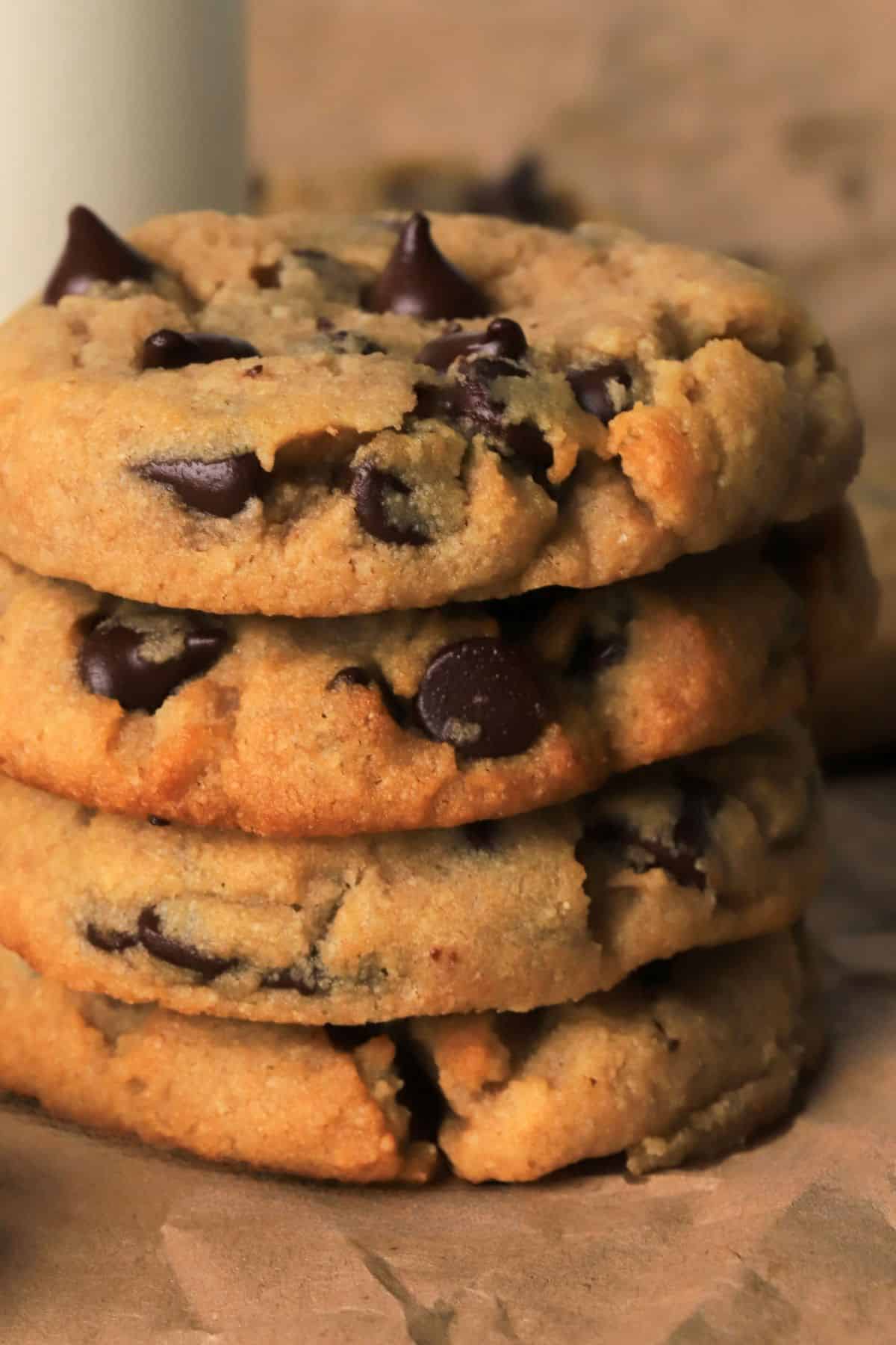 Low carb chocolate chip cookies stacked on top of each other next to a glass of milk.