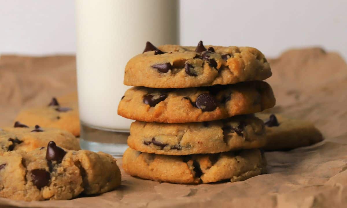 Low carb chocolate chip cookies stacked on top of each other next to a glass of milk.