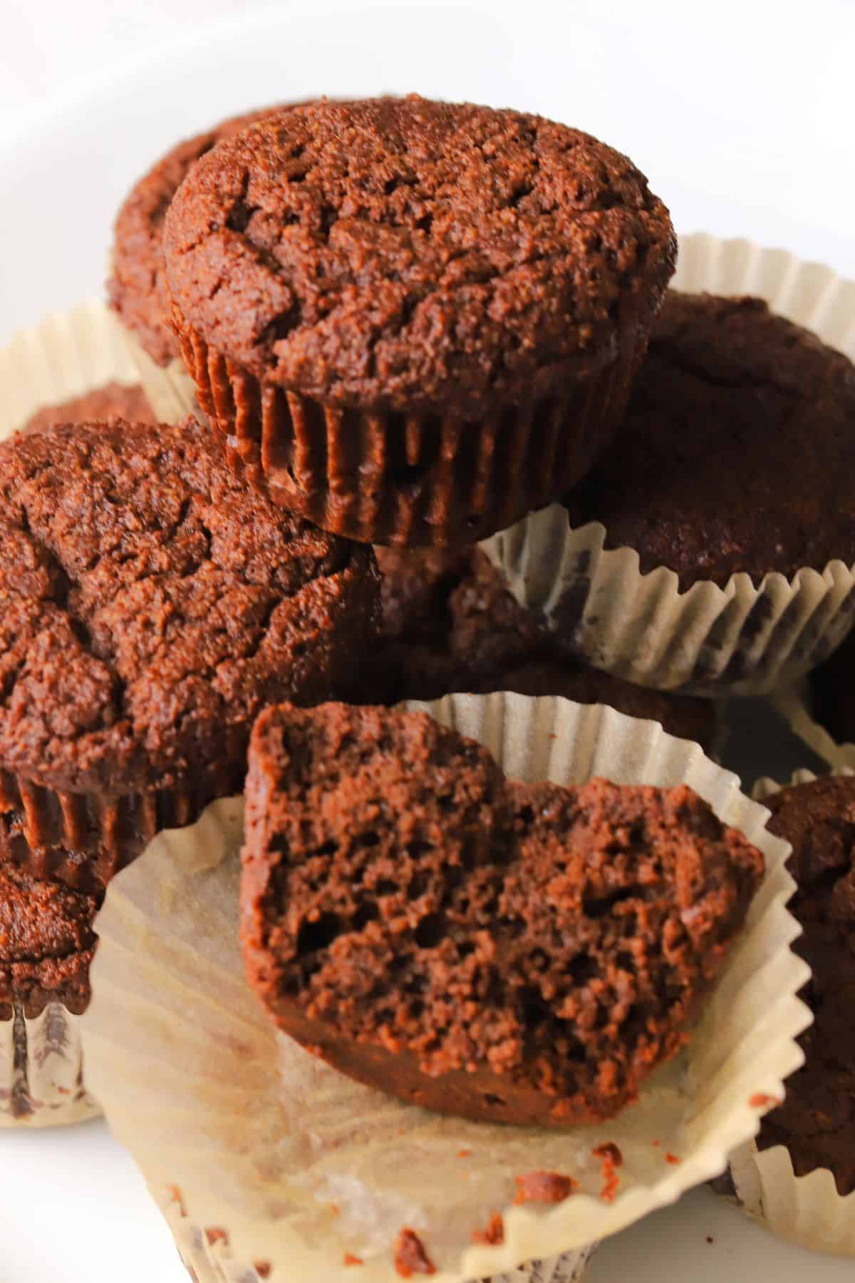 Half a low carb double chocolate muffin stacked on top of other muffins.