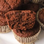 Half a low carb double chocolate muffin stacked on top of other muffins.
