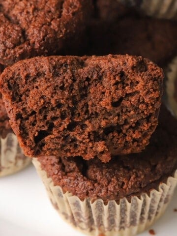Half a low carb double chocolate muffin stacked on top of other muffins.