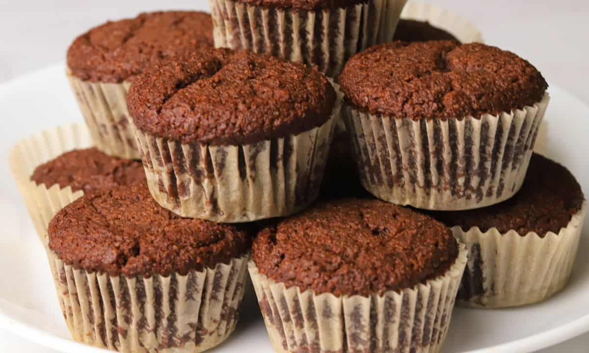 Low carb double chocolate muffins stacked on a white plate.