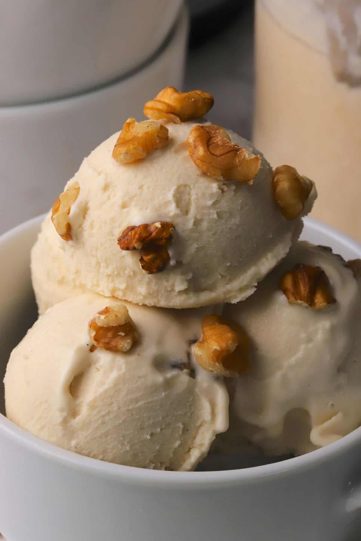 Scoops of low carb maple walnut ice cream in a bowl topped with walnut pieces.