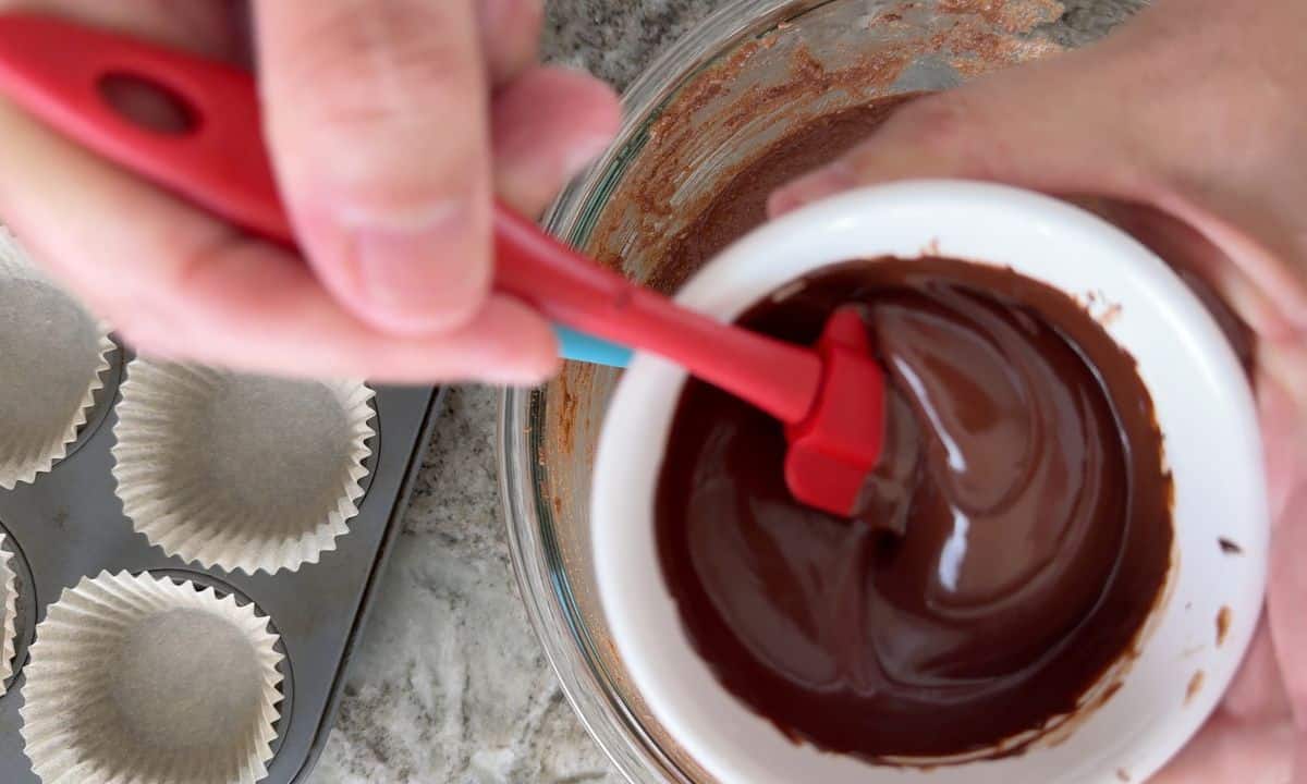 Stirring the melted chocolate in a white bowl.