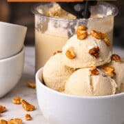 Scoops of low carb maple walnut ice cream in a bowl topped with walnut pieces next to the ninja creami pint.