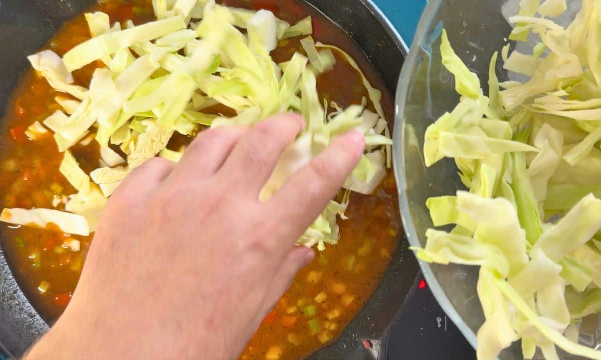 Adding the cabbage strips to the skillet.