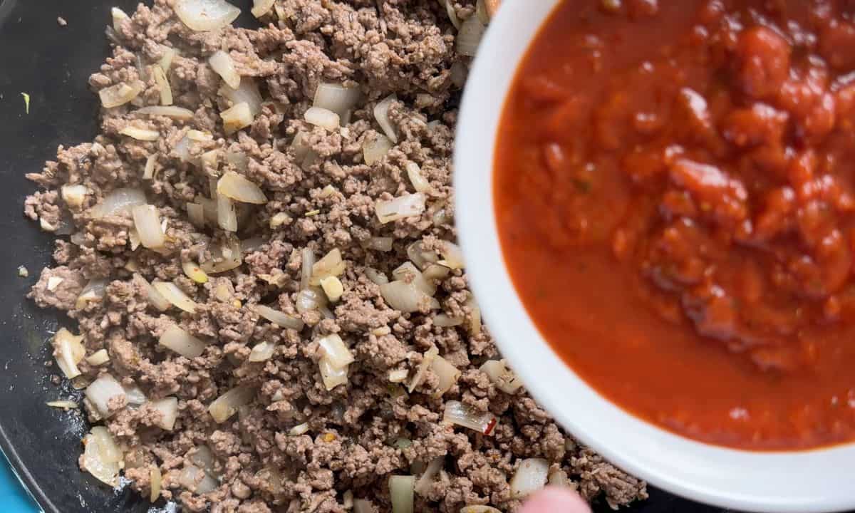 Beef in a pan with a bowl of sauce.