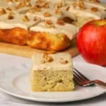 A square of low carb apple spice cake on a plate next to an apple.