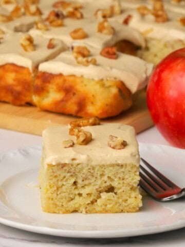 A square of low carb apple spice cake on a plate next to an apple.