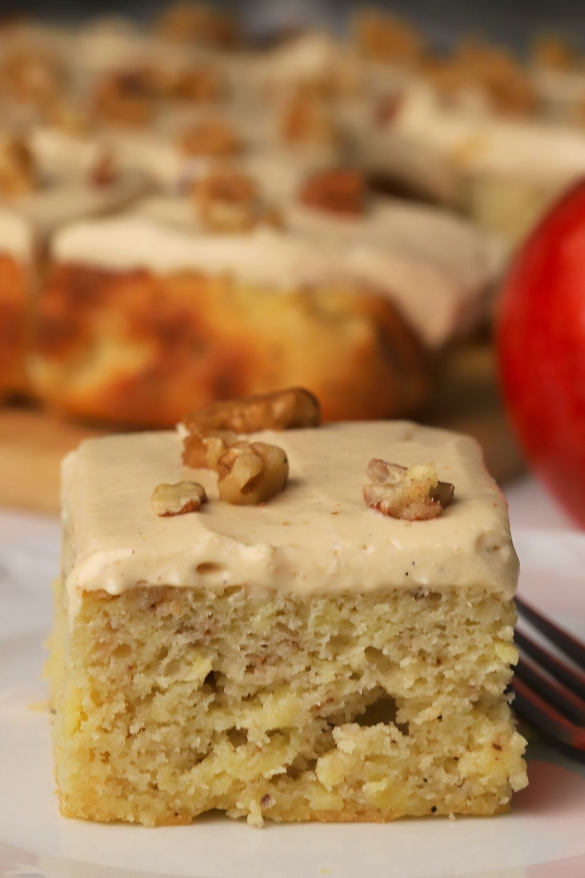 A square of low carb apple spice cake on a plate next to an apple.