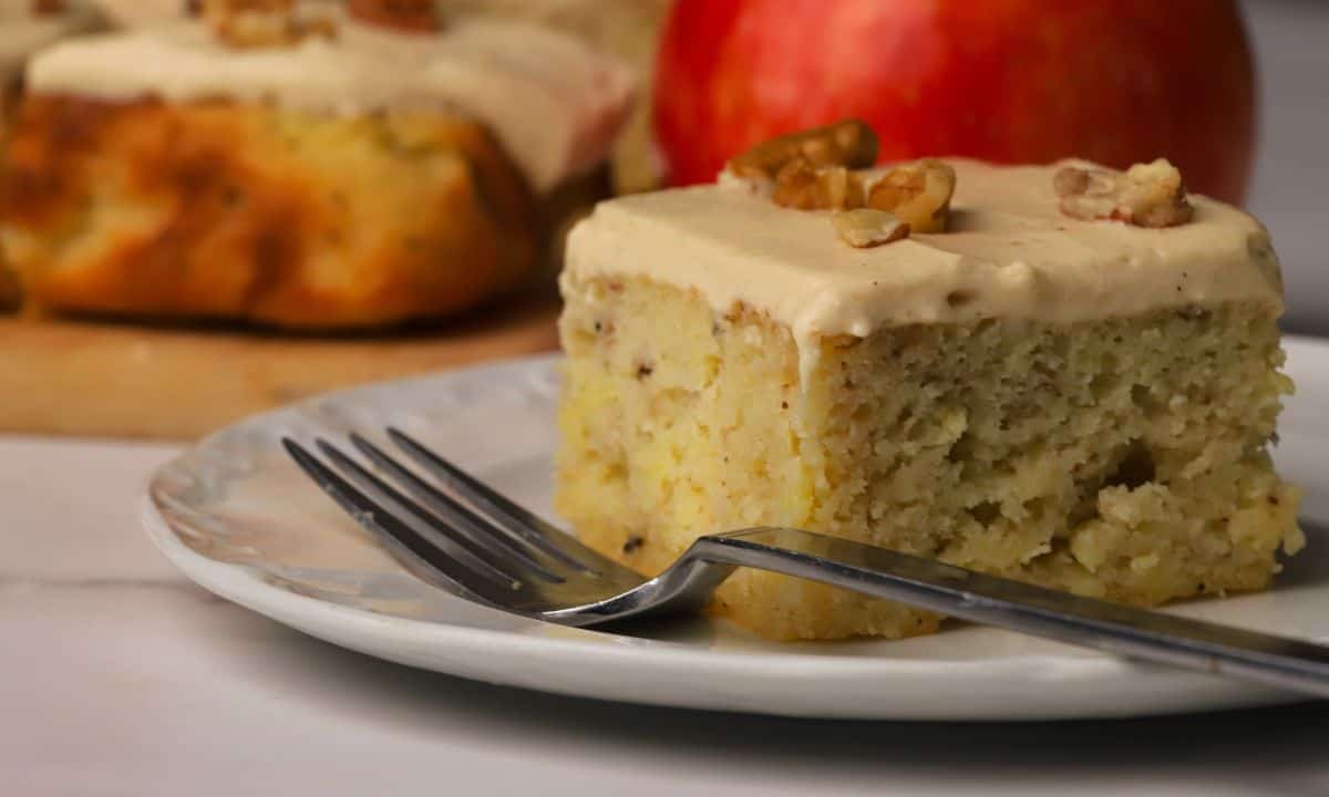 A square of low carb apple spice cake on a plate next to an apple.