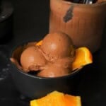 Scoops of low carb chocolate orange ninja creami ice cream in a bowl with orange segments.