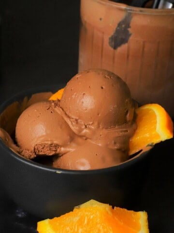 Scoops of low carb chocolate orange ninja creami ice cream in a bowl with orange segments.