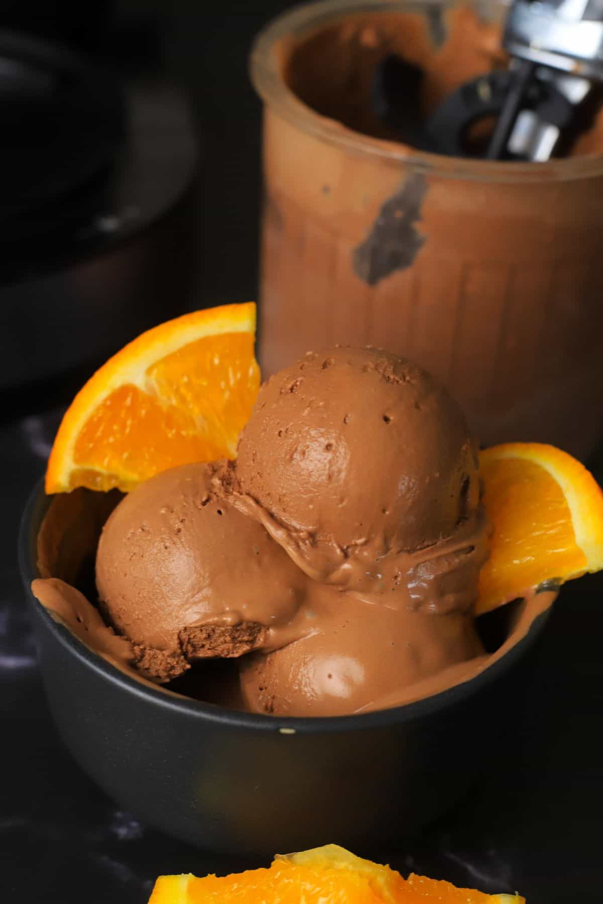 Scoops of low carb chocolate orange ninja creami ice cream in a bowl with orange segments.