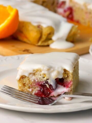 Closeup of a square of the low carb cranberry orange spice cake on a plate with a fork.