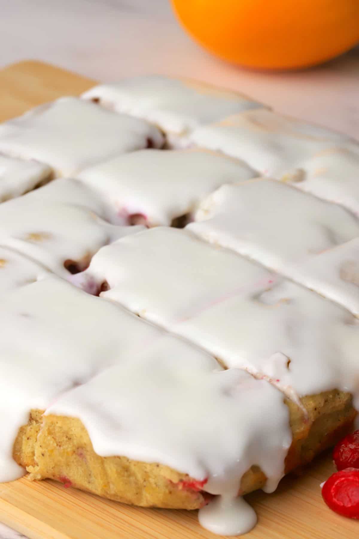 The low carb cranberry orange spice cake cut into squares with an orange in the background.