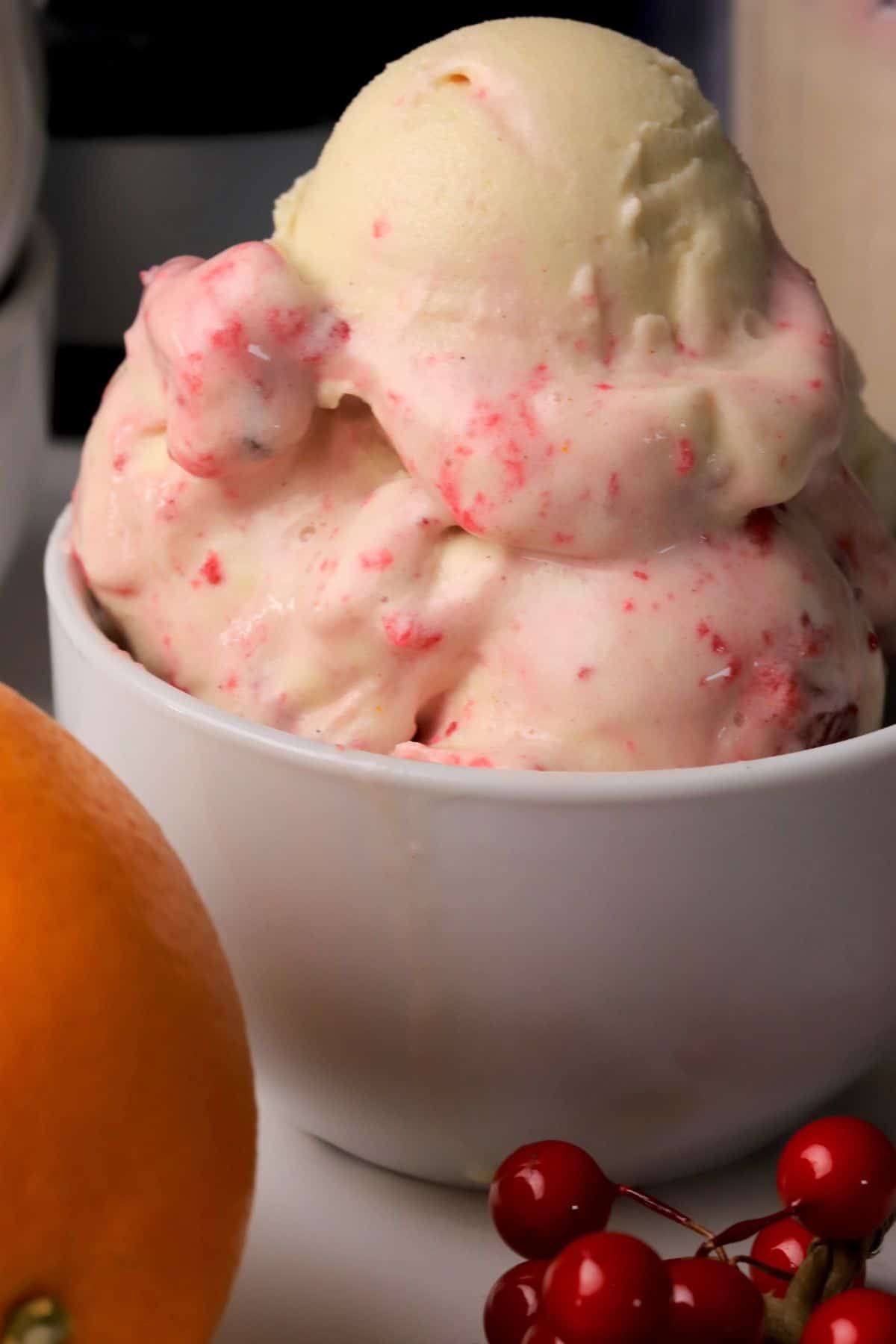 Close up of low carb cranberry orange spice ice cream in a bowl next to an orange.