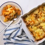 A slice of the low carb italian beef and cabbage cheesy casserole on a plate next to the casserole dish.