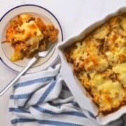 A slice of the low carb italian beef and cabbage cheesy casserole on a plate next to the casserole dish.