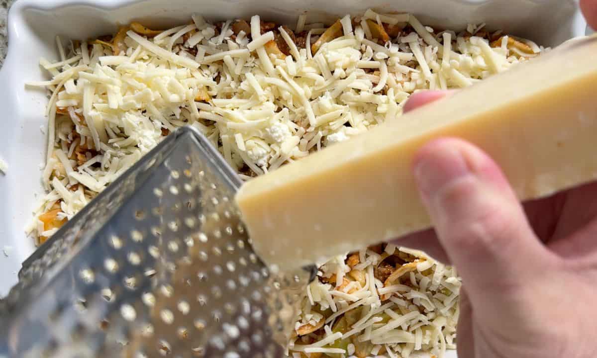 Grating the parmesan over the casserole dish.